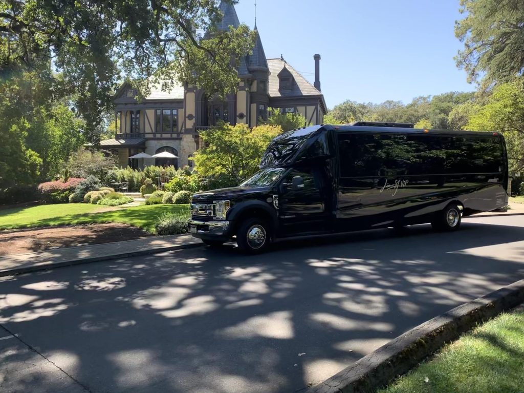 Black shuttle bus parked in front of a chateau-style estate