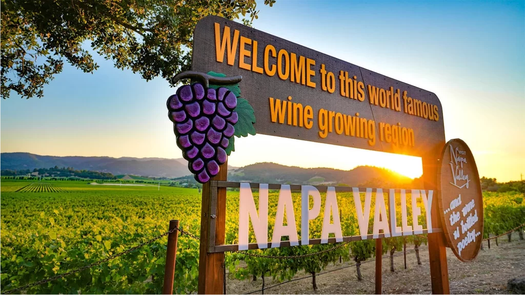 Welcome to Napa Valley sign above vineyards at sunset