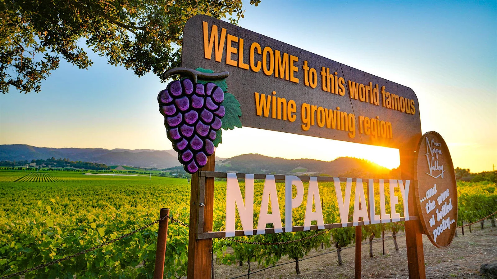 Welcome to Napa Valley sign above vineyards at sunset