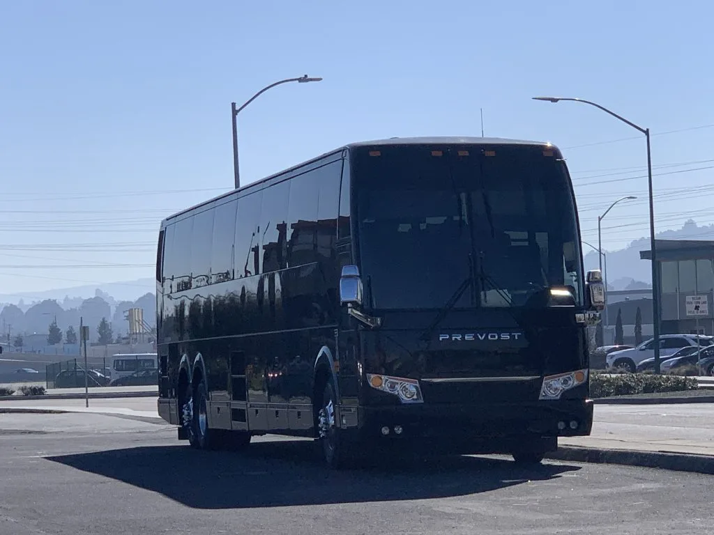Black Prevost motorcoach front view in a parking lot