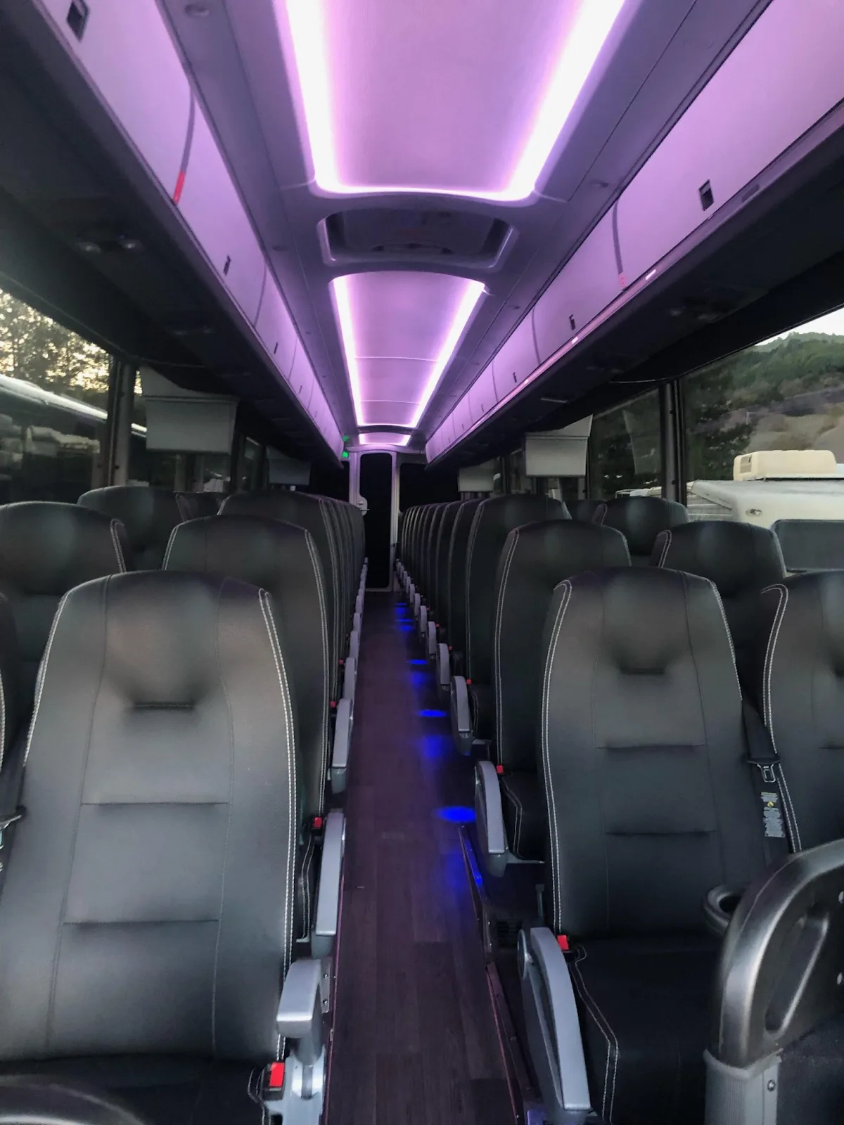 MCI coach interior with black leather seats and purple ceiling lighting