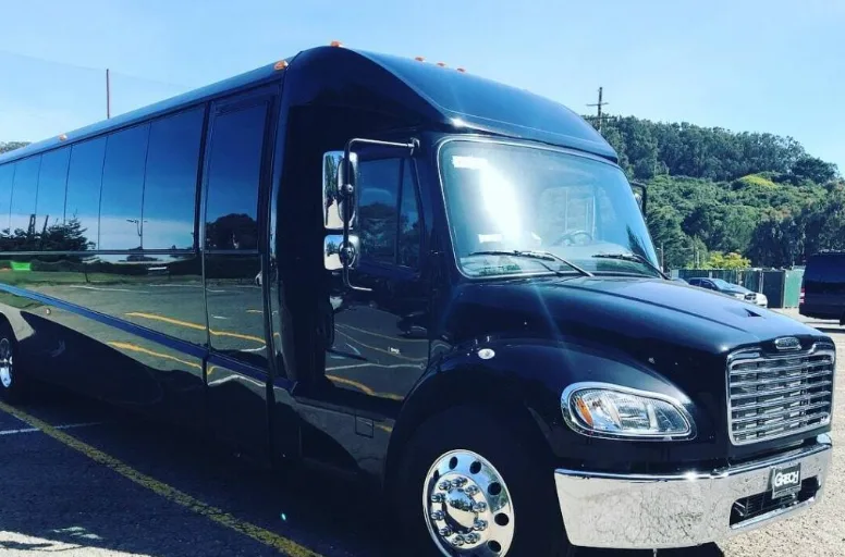 Black executive mini coach parked under a blue sky