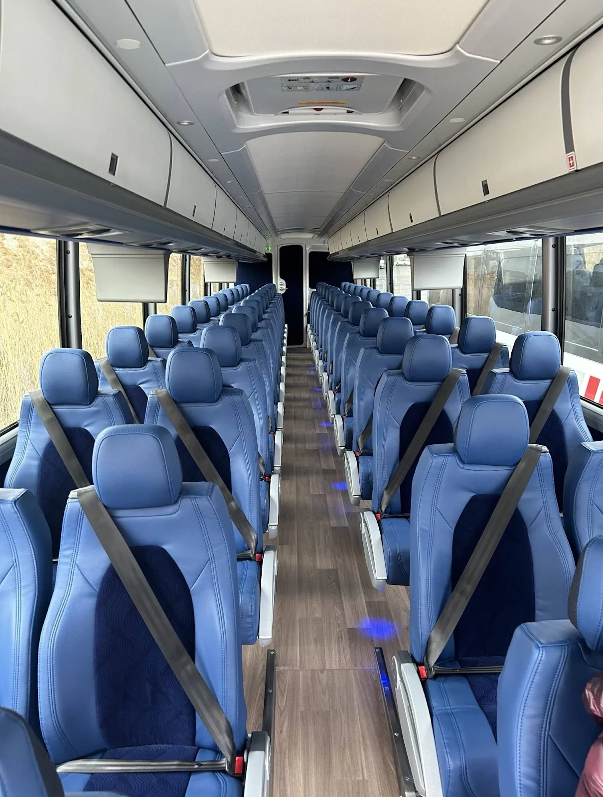 Coach bus interior with blue seats and a wood-look aisle