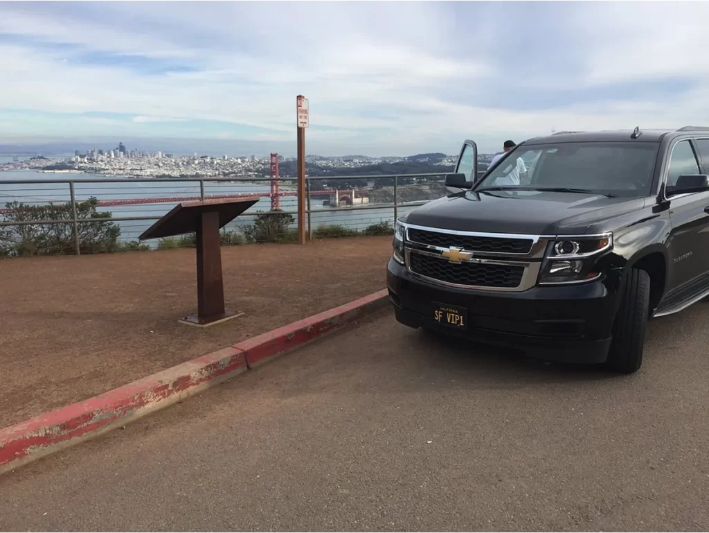 Black Chevrolet Suburban at a scenic overlook with the Golden Gate Bridge behind
