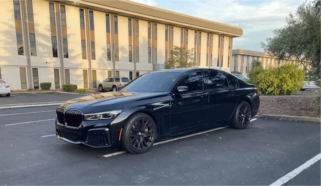 Black BMW 7 Series sedan parked outside an office building