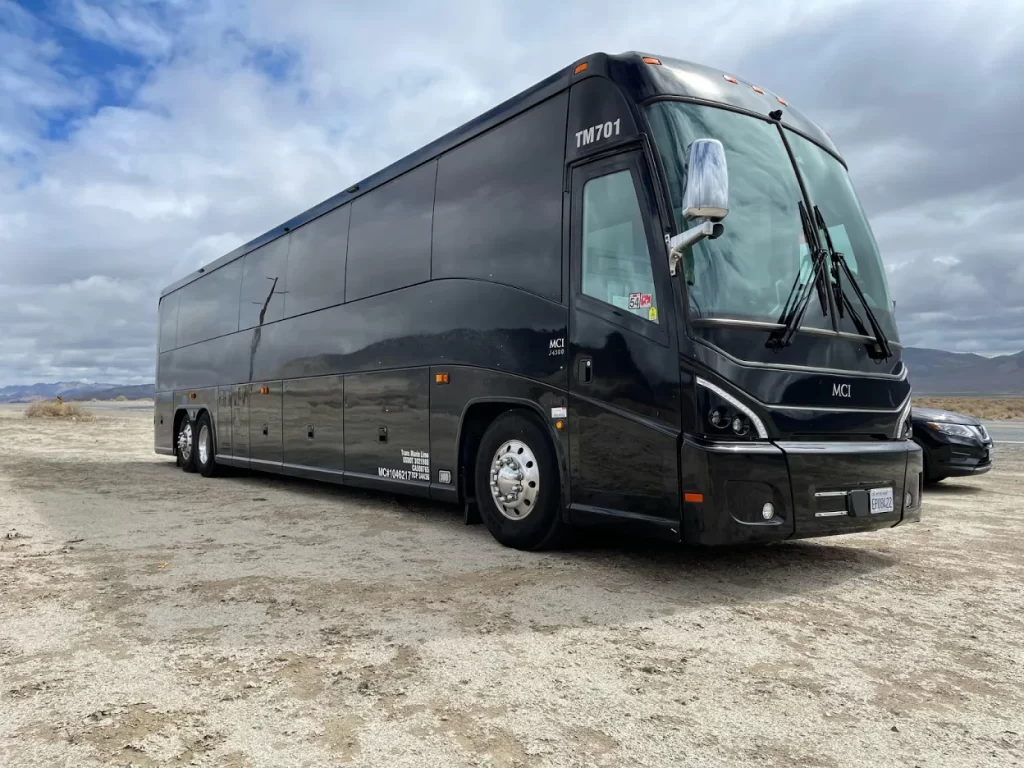 Black MCI motorcoach bus parked on open ground
