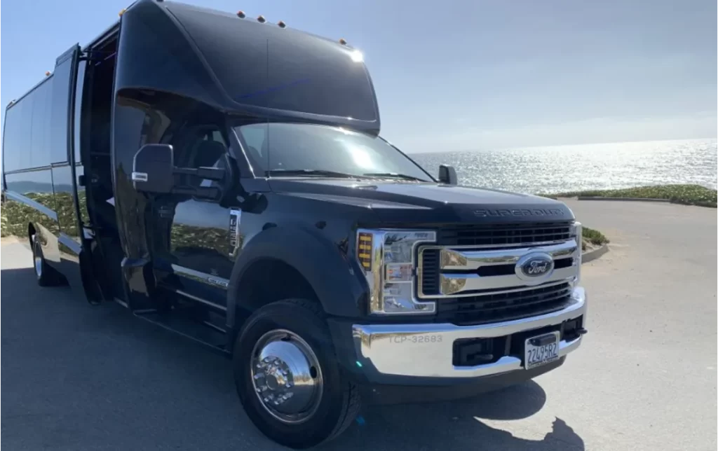 Black Ford mini bus with open door parked by the ocean