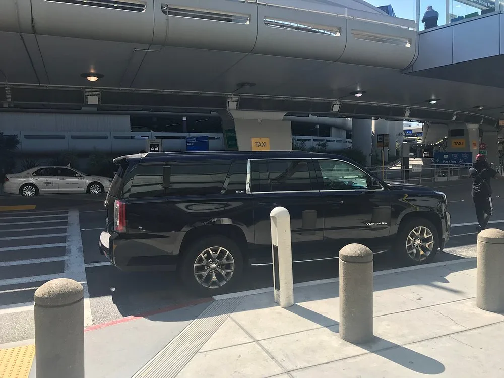 Black SUV at the curb of an airport terminal departures area