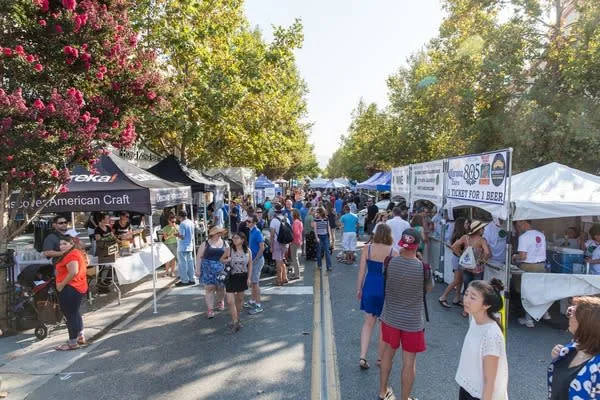 Crowds walking through a street festival with vendor tents