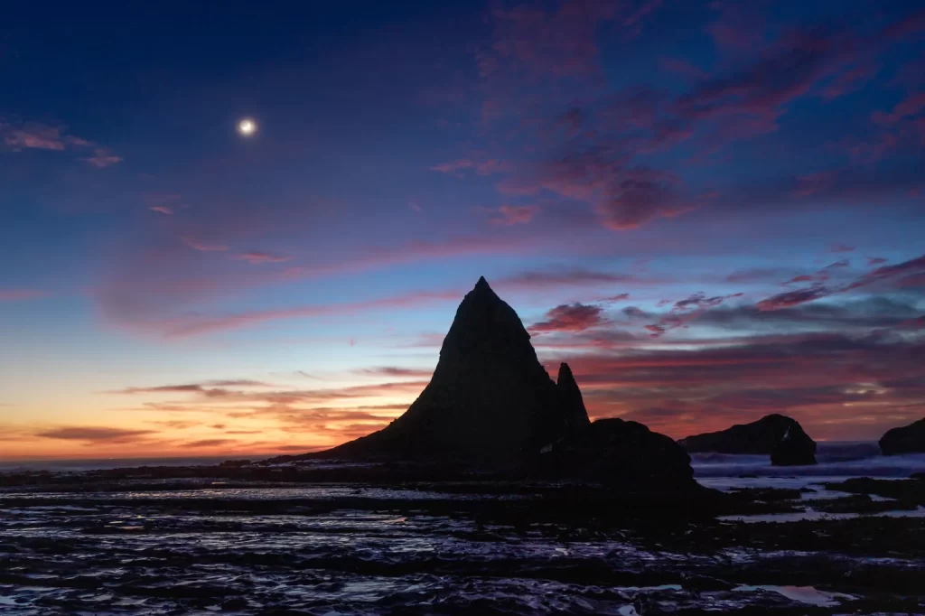 Rock formation silhouetted at sunset on the California coast