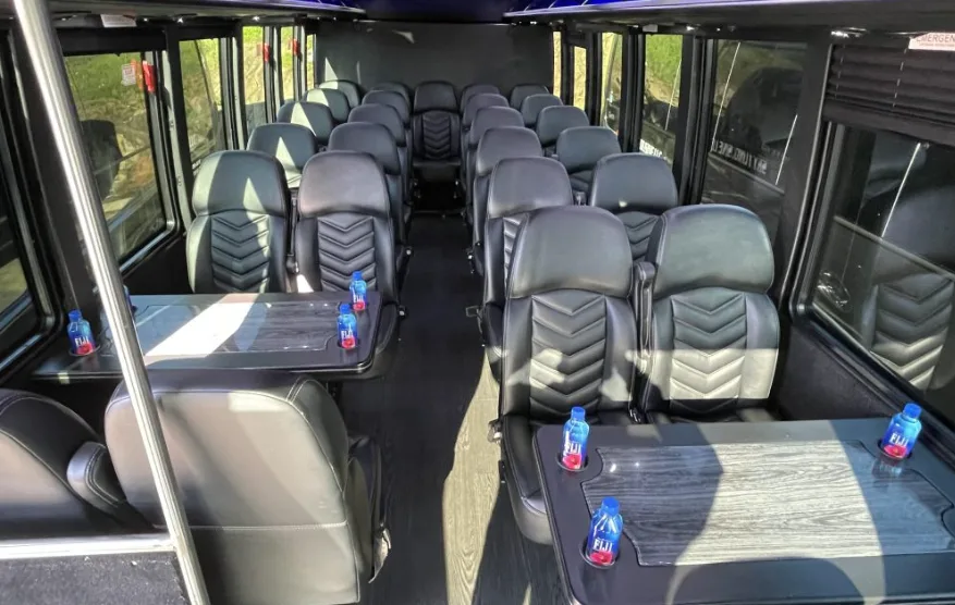 Mini coach interior with leather seats, tables and bottled water