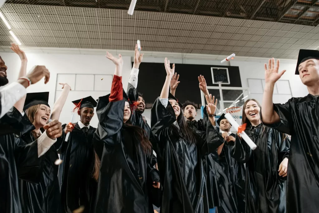 Graduates in black gowns tossing caps and celebrating
