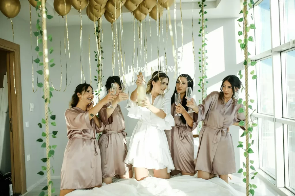Bride and bridesmaids in satin robes toasting with champagne at a bachelorette party