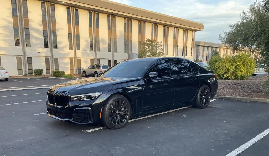 Black BMW 7 Series sedan parked outside an office building