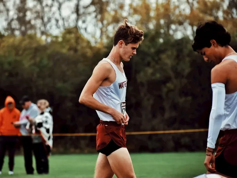 Cross-country runners in race singlets on a grass course